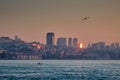 Houses on the sea coast at dawn. View of the city from the sea, boats, seagulls skyscrapers at sunrise. Royalty Free Stock Photo
